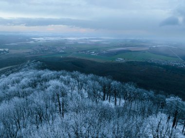 Aerial view of winter forest with frost or freeze line. Freezing on hills. Drone view of snowy landscape. clipart