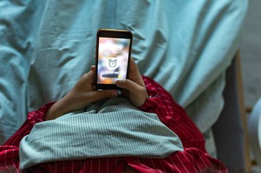 Akşam uyumadan önce alarm kuran bir kadın. Uyku rutini kavramı. Uykusuzluk yetişkinler arasında bir uyku problemi.