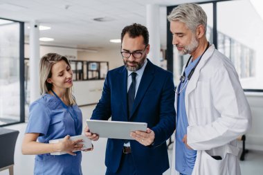 İlaç satış temsilcisi tıp binasındaki doktorlara yeni ilaçları tablette gösteriyor. Özel sağlık kliniği müdürü doktorlarla konuşuyor. Cömert bağışçı