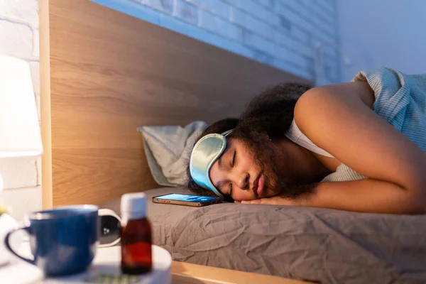 Woman sleeping with sleep mask, using sleeping pills, melatonin supplements. Concept of sleep routine. Insomnia a sleep problems among adults.