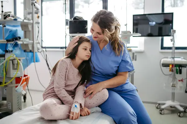 Supportive doctor soothing a worried girl patient in emergency room. Concept of emotional support and friendliness for young kid patient.