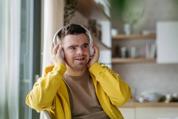 Hombre Joven Con Síndrome Escuchando Música Través Auriculares Sentado Cocina —  Fotos de Stock