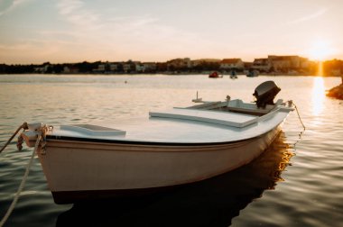 Sakin sularda küçük bir tekne, limanda demirli, gün batımında rıhtımda..