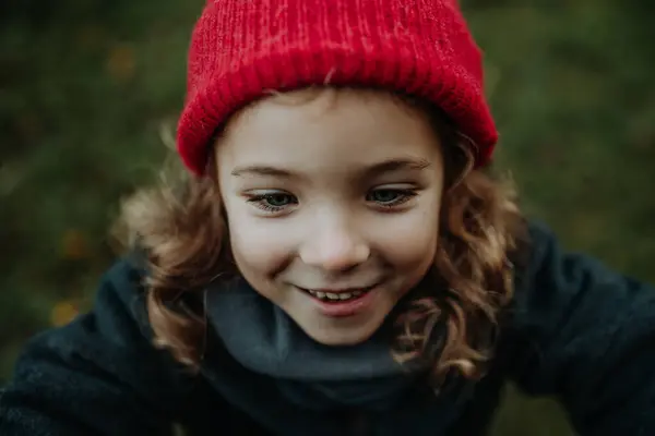 Portrait of little girl in red knitted hat. Red riding hood girl or little redcap lookalike.