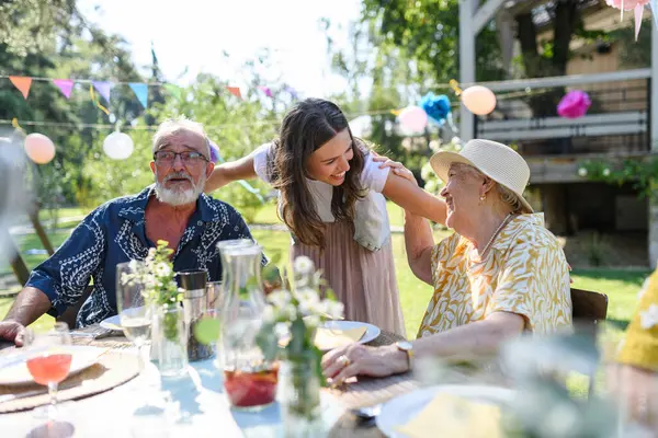 祖父母と話す成熟した孫娘は 久しぶりに再会します ガーデンパーティーで集まるファミリー — ストック写真