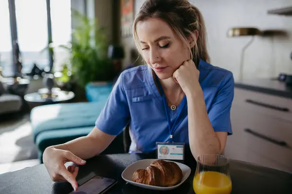 女护士或女医生早上开始准备工作 一边吃早饭一边用智能手机打滚 然后穿着洗发水去上班 医护人员的工作与生活平衡 — 图库照片