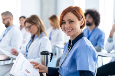Bir grup doktor konferansta, tıbbi ekip oturuyor ve sunucuyu dinliyor. Bir eğitim etkinliğine katılan tıp uzmanları, kurul odasında seminer.