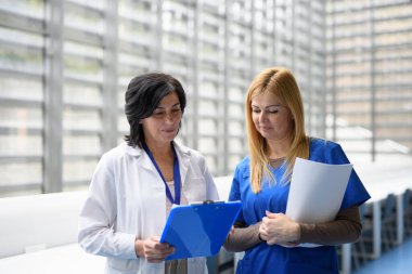 İki kadın doktor test sonuçlarını tartışıyor, koridorda yürüyorlar. İş arkadaşları hasta teşhisini tartışıyor. Tıp bilimindeki kadınlar
