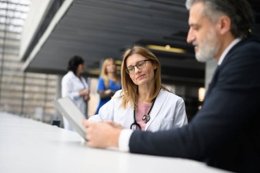 Doktorlar ilaç satış temsilcisiyle konuşuyor, el sıkışıyor, yeni ilaç ürünlerini sunuyorlar. Hastane müdürü, yönetici kadın doktorla konuşuyor..