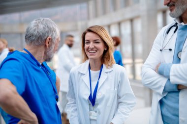 Bir grup doktor konferans sırasında konuşuyor, araştırma bulgularını tartışıyorlar. Tıbbi ağ. Bir eğitim etkinliğine katılan tıp uzmanları, toplantı odasında seminer. Sağlık hizmetlerinde yaş ve cinsiyet eşitliği.