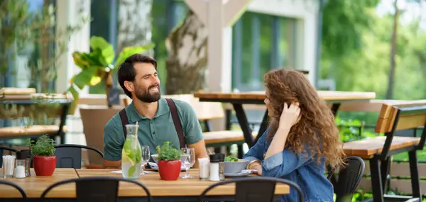 Young couple at date in restaurant, sitting on restaurant terrace. Boyfriend and girlfriend enjoying springtime, having lunch or brunch outdoors, outdoor seating for dining. Banner with dopyspace.