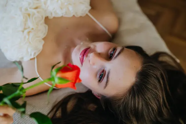 性感女人躺在床上闻着美丽的红玫瑰 情人节的概念 爱情与爱情 — 图库照片
