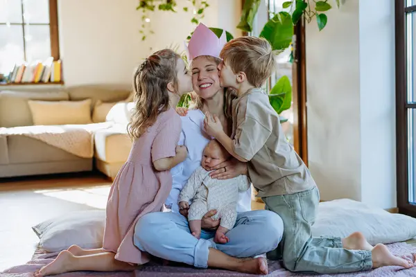 母亲生下王后后 女儿和儿子正在亲吻妈妈 头上戴着纸冠 对母亲的爱戴 母亲节的概念和妇女的力量 — 图库照片