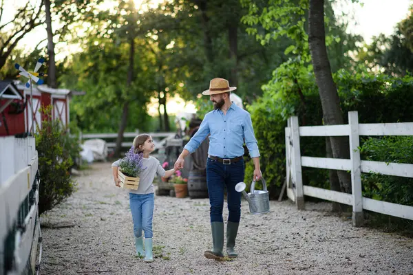 農民の家族 若い娘が家族の農場を歩き回り 水やり缶を手に入れた 多世代農業の概念 ロイヤリティフリーのストック画像