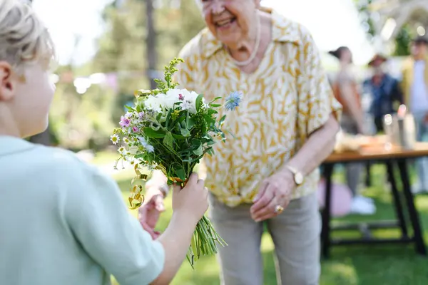 Vacker Seniorfödelsedagskvinna Som Får Blommor Från Sonson Barnbarn Begreppet Trädgård — Stockfoto