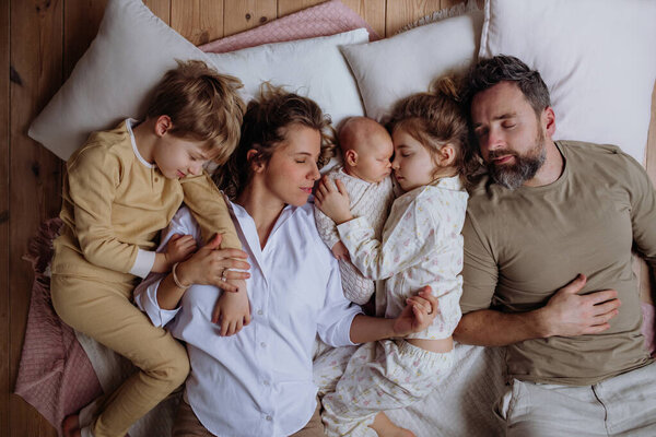 Top view of family sleeping in bed with kids and newborn baby. Perfect moment. Strong family, bonding, parents unconditional love for their children.