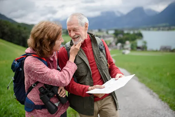 アクティブな高齢者のカップルが山で一緒にハイキングし 自然を楽しんでいます 地図上のルートを見ているシニア観光客 — ストック写真