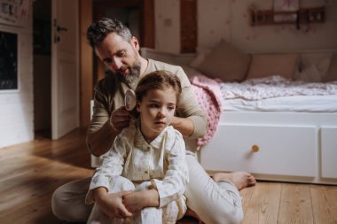 Baba kızının saçını örüyor, yatmadan önce saçlarını tarıyor. Bekar bir baba kızının saç stiliyle ilgileniyor..