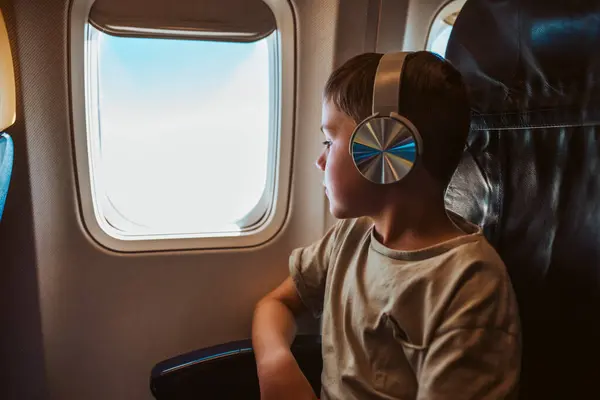 Anak Laki Laki Dengan Headphone Adalah Melihat Keluar Jendela Pesawat — Stok Foto