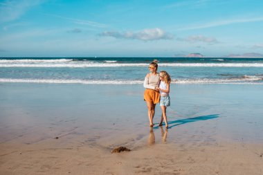 Kumsalda kolu kırık bir annesi olan bir kız. Tatil köyünde aile tatili sırasında yaralanmış. Aile plajı yaz tatili konsepti.