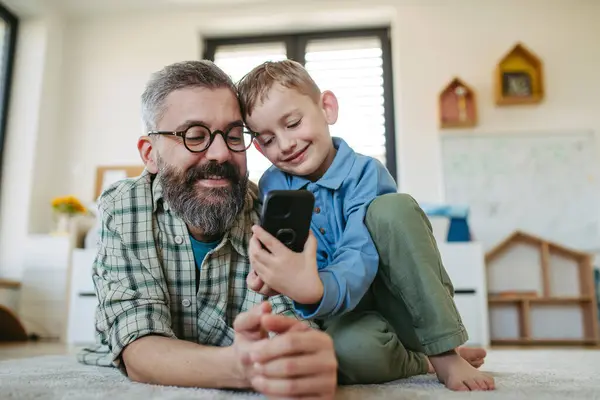 Anak Kecil Menonton Film Kartun Smartphone Dengan Ayah Berbaring Lantai — Stok Foto