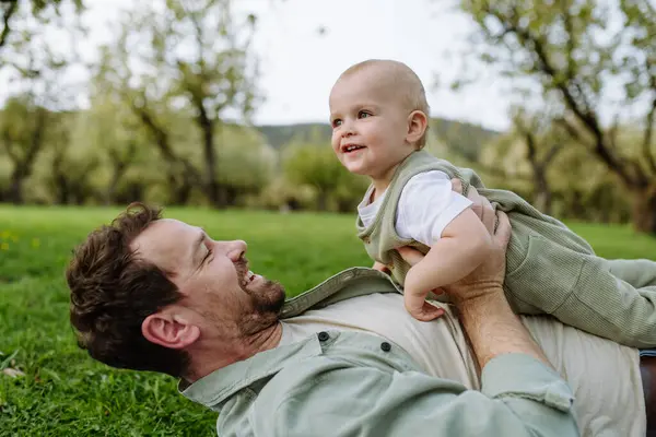 Bir Baba Küçük Bebekle Yalan Söylüyor Baharda Çimenlerde Eğleniyor Babalar - Stok İmaj