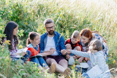 Genç öğrenciler biyoloji dersi sırasında doğa, orman ekosistemini öğreniyorlar, yabani bitkileri gözlemliyorlar, not alıyorlar. Açık hava eğitimi sırasında öğretmenlik yapmaya adanmıştır. Öğretmenler Günü.