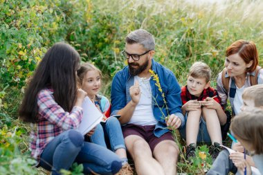 Genç öğrenciler biyoloji dersi sırasında doğa, orman ekosistemini öğreniyorlar, yabani bitkileri gözlemliyorlar, not alıyorlar. Açık hava eğitimi sırasında öğretmenlik yapmaya adanmıştır. Öğretmenler Günü.