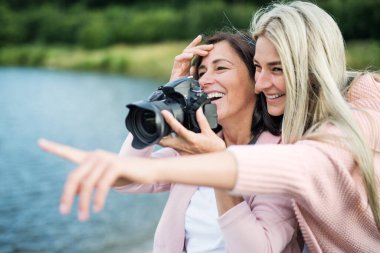 Yetişkin kız, annesine fotoğraf çekmeyi öğretiyor. Teknolojiyi anlatıyor, gülüyor. Anneler Günü.