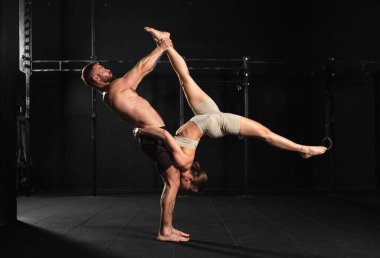 Genç bir erkek ve kadın için akroyoganın ortak spor aktivitesi. Çift spor salonunda birlikte egzersiz yapıyor, karmaşık manevralar yapıyor..