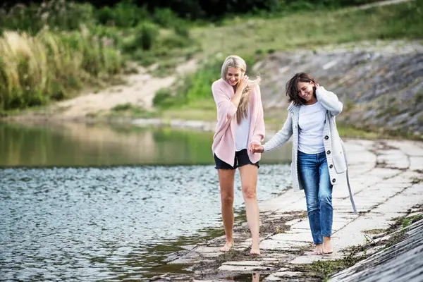 大女儿和她母亲在一起 妈妈和女儿在外面赤脚行走在湖水的水库 湖堤上 无条件的 深刻的母爱 母亲节概念 图库图片