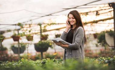 Güzel bir işletme sahibi müşteriyle telefonda konuşuyor, çiçek ve fidanlar sipariş ediyor. Küçük bir sera işi. Bahçe mevsiminde çok çeşitli bitkiler sunuyor..