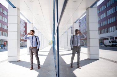 Şehir caddesinde yürürken, ofise giderken akıllı telefondan arayan yakışıklı bir iş adamı. Müdür gülümsüyor, şehir ortamında açık havada..