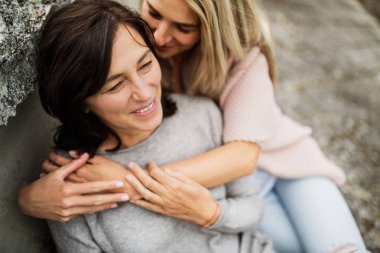 Yetişkin kız, annesiyle dışarıda vakit geçiriyor. Güzel kız birbirine sevgiyle sarılıyor. Koşulsuz, derin anne sevgisi, Anneler Günü konsepti.