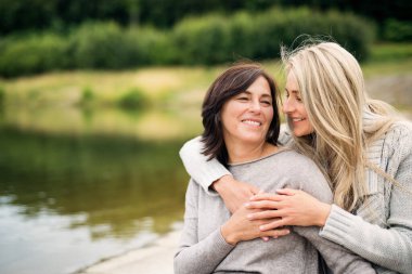 Yetişkin kız, annesiyle dışarıda vakit geçiriyor. Güzel kız birbirine sevgiyle sarılıyor. Koşulsuz, derin anne sevgisi, Anneler Günü konsepti.
