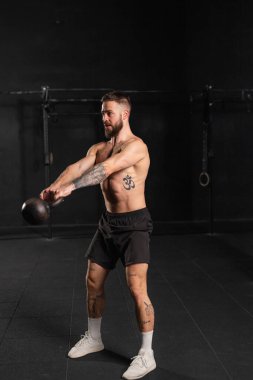 Kettlebell salıncakları yapan bir adam, iki elinde de kettlebell tutuyor. Güç egzersizi. Fiziksel ve zihinsel sağlık için rutin çalışma.