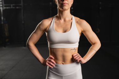 Spor kıyafetleri giymiş, spor salonunda kaslı genç bir kadın. Fiziksel ve zihinsel sağlık için rutin çalışma.