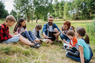 Öğrenciler saha dersi sırasında yenilenebilir rüzgar enerjisini öğreniyorlar. Açık havada aktif eğitim, genç öğrencilere ekoloji ve sürdürülebilirlik, çevre koruma hakkında bilgi vermektedir..