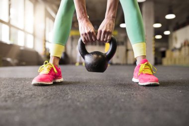 Kettlebell salıncakta sallanan sporcu kadın ellerinde kettlebell tutuyor, yakın çekim. Kadınlar için rutin çalışma fiziksel ve zihinsel sağlık.