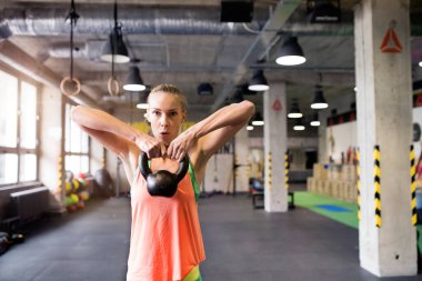 Kettlebell salıncakta sallanan güzel bir spor kadını elinde kettlebell tutuyordu. Kadınlar için rutin çalışma fiziksel ve zihinsel sağlık