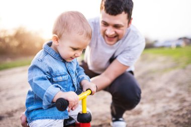 Çocuk bisiklete binmeyi öğreniyor, baba ona yardım ediyor. Babalar Günü.