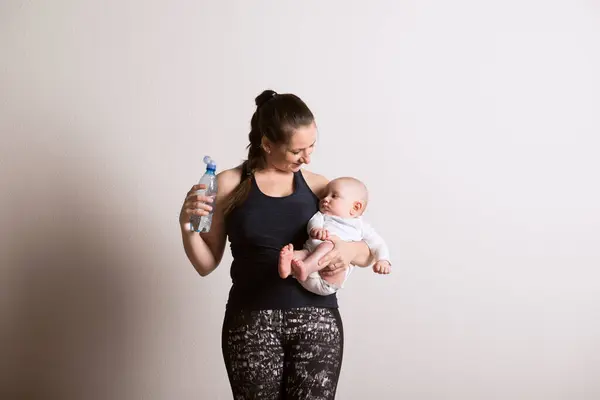 Woman Drinkng Water Home Exercise Mother Baby Mommy Workout Physical lizenzfreie Stockfotos