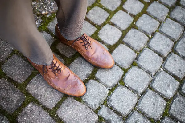 Kahverengi deri ayakkabılı, açık havada iş adamının ayaklarının en üst görüntüsü..