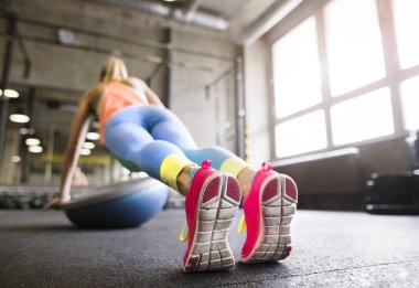 Spor salonunda denge topu üzerinde egzersiz yapan, şınav çeken güzel bir kadın. Kadınlar için rutin çalışma fiziksel ve zihinsel sağlık