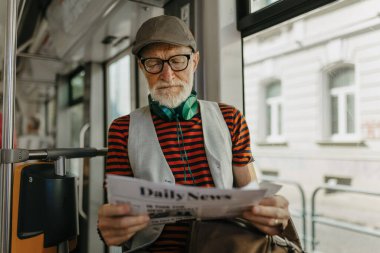 Yaşlı bir adam otobüsle şehri geziyor, gazete okuyor. Büyükşehir banliyösü tramvayla markete gidiyor, toplu taşımayı kullanıyor..