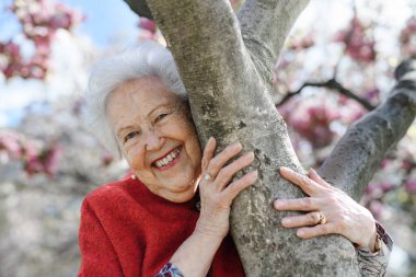 Manolya ağacının yanında duran yaşlı güzel bir kadının portresi. Parkta, rahatlatıcı bir an yaşıyor. Büyükannem bahar havasının keyfini çıkarıyor..