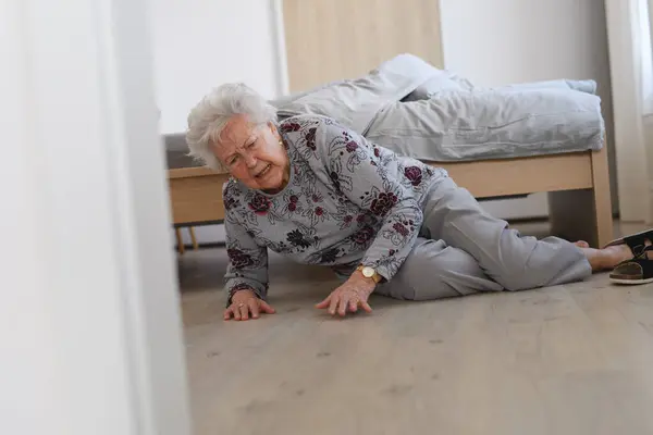 stock image Elderly woman tripped and fell from bed, injured herself, broke hip.