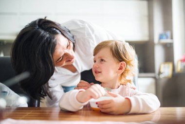 Büyükanne, anne babaları işteyken torunlarına bakıyor. Küçük tatlı kıza yemek servisi yapıyorlar. Büyükanne ve büyükbabanın bakımı kavramı.