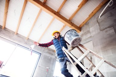 Merdivenden düşen adam. İnşaat alanında çalışan bir adamın kazası. İş yerinde yaralanma ve kaza.