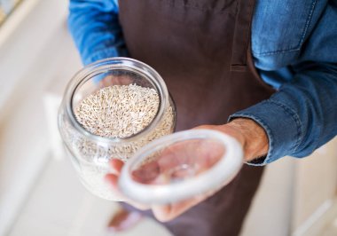 Yeniden kullanılabilir konteynırlar kullanarak paketsiz mağazada çalışan yakışıklı bir adam. Paketsiz mal ve sürdürülebilir alternatif sunan sıfır atık mağazası.